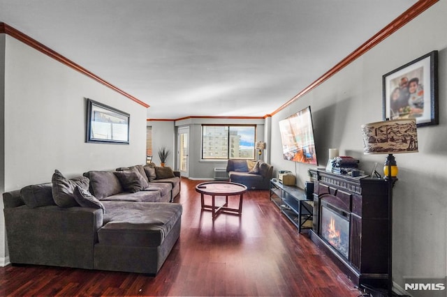 living area featuring dark wood-type flooring, a glass covered fireplace, ornamental molding, and baseboards