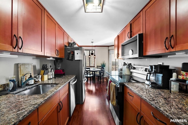 kitchen featuring dark wood-style flooring, crown molding, appliances with stainless steel finishes, a sink, and dark stone countertops