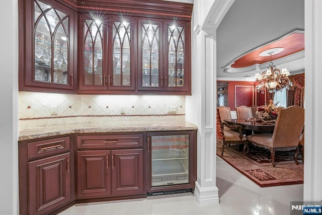 bar with wine cooler, ornamental molding, backsplash, hanging light fixtures, and a notable chandelier