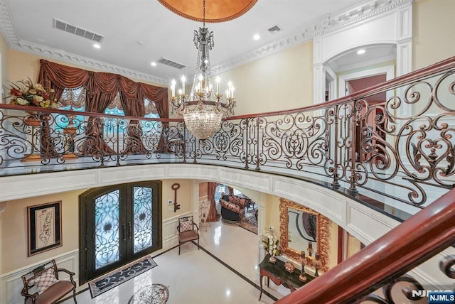 foyer entrance with visible vents, arched walkways, a chandelier, and french doors