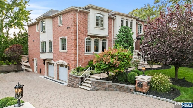 view of front of home with driveway, an attached garage, stairs, and brick siding