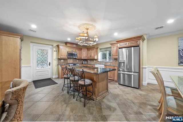 kitchen featuring stainless steel appliances, visible vents, hanging light fixtures, and a notable chandelier