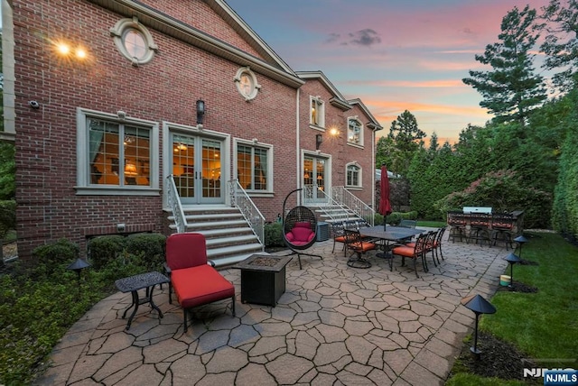 rear view of house with entry steps, outdoor dining space, a patio area, and brick siding