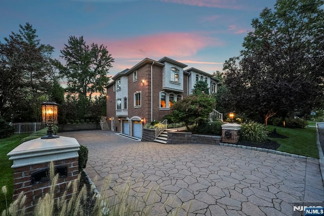 exterior space with a garage, decorative driveway, and brick siding