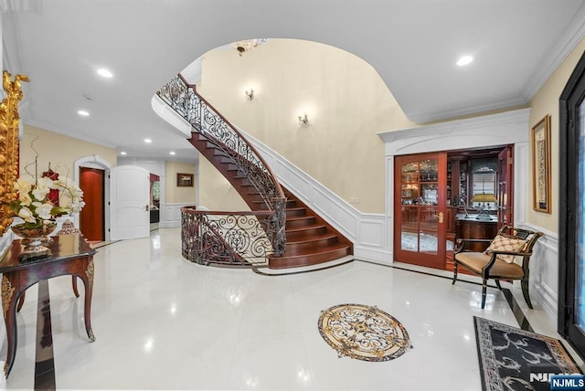 foyer entrance featuring arched walkways, a wainscoted wall, stairs, a decorative wall, and recessed lighting