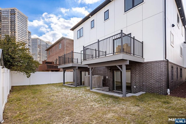 back of house featuring brick siding, a lawn, cooling unit, and a fenced backyard