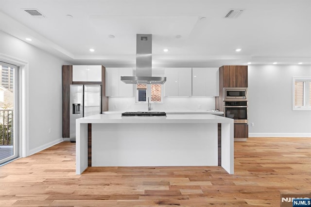 kitchen with stainless steel appliances, modern cabinets, island range hood, and white cabinets