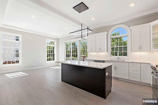 kitchen featuring light countertops, a kitchen island, decorative light fixtures, and white cabinetry