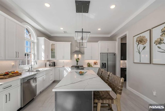 kitchen featuring glass insert cabinets, a center island, hanging light fixtures, stainless steel appliances, and white cabinetry