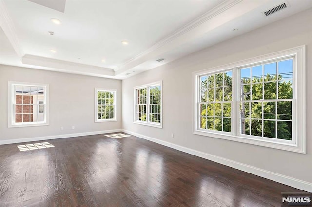 unfurnished room featuring a tray ceiling, dark wood-type flooring, visible vents, and baseboards