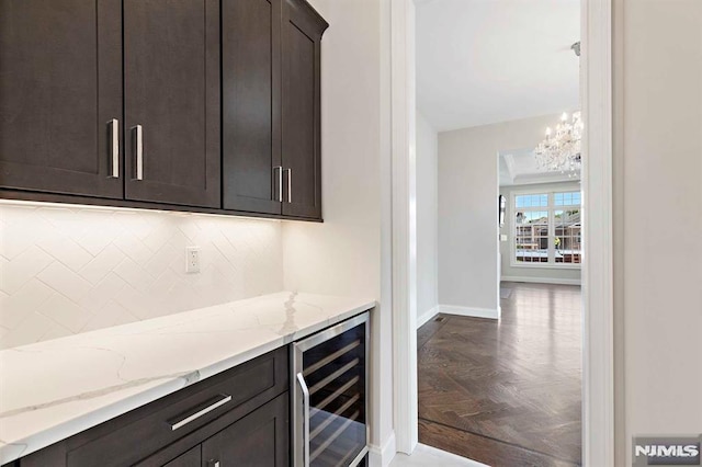 bar with baseboards, wine cooler, a chandelier, and decorative backsplash