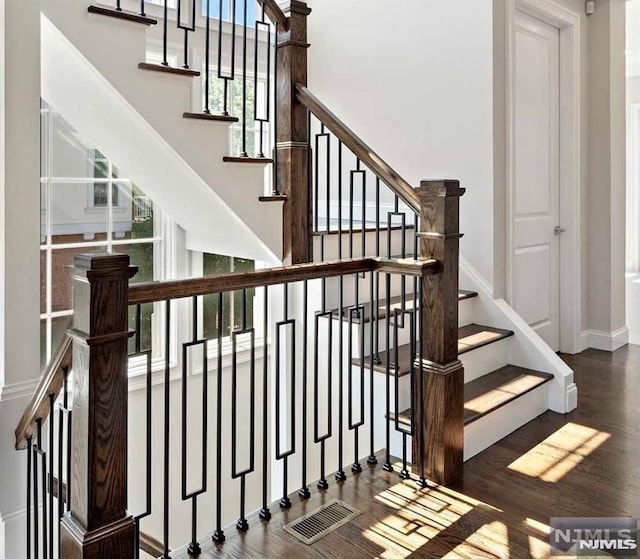 stairway with a high ceiling and wood finished floors