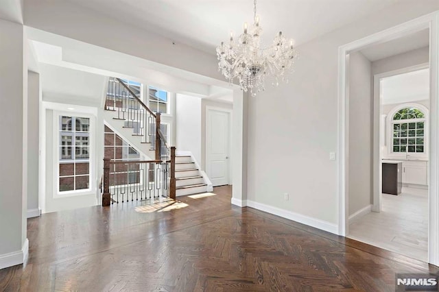 unfurnished dining area with a notable chandelier, stairway, and baseboards