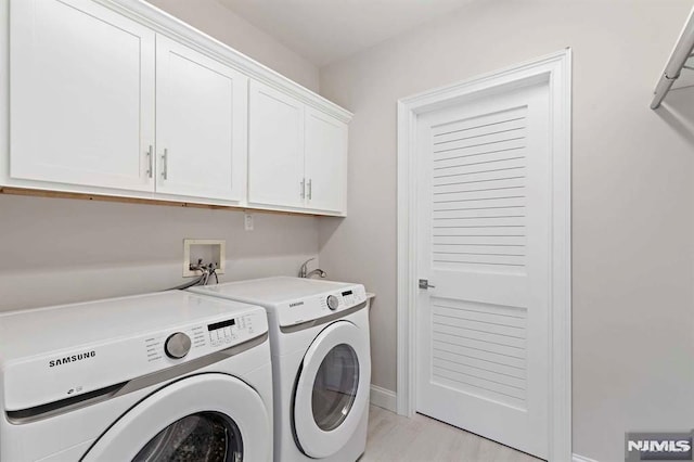 clothes washing area featuring washing machine and dryer and cabinet space