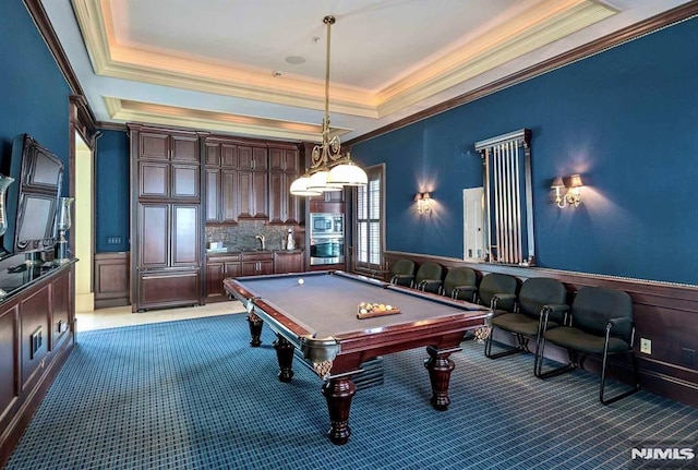 game room featuring billiards, a raised ceiling, light colored carpet, wainscoting, and ornamental molding