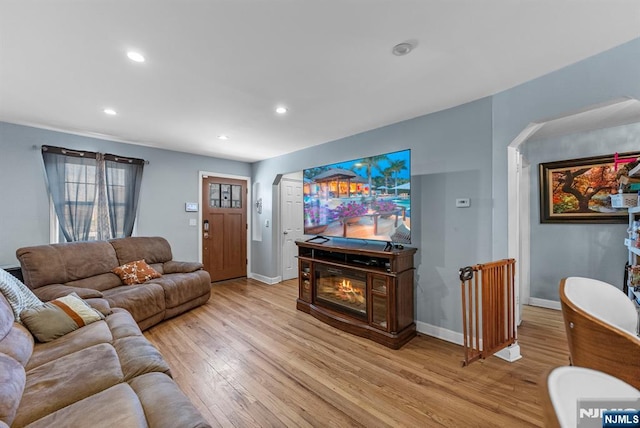 living room with light wood-style floors, recessed lighting, a glass covered fireplace, and baseboards