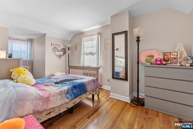 bedroom with lofted ceiling, multiple windows, light wood-type flooring, and baseboards