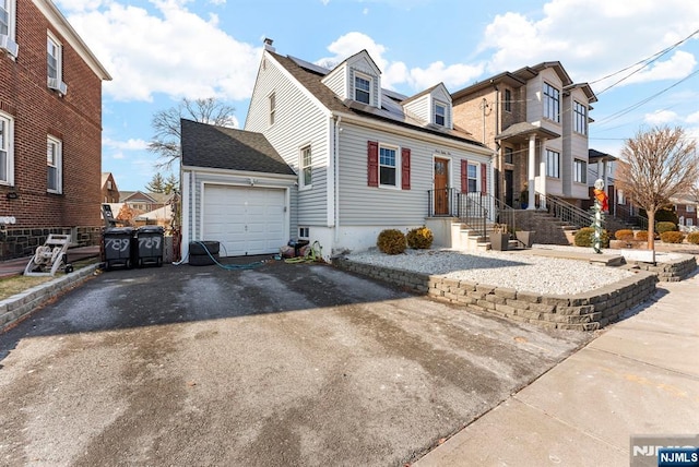 view of front facade featuring aphalt driveway, a residential view, a shingled roof, and a garage