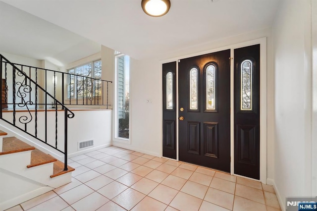 entrance foyer featuring light tile patterned floors, stairway, visible vents, and baseboards