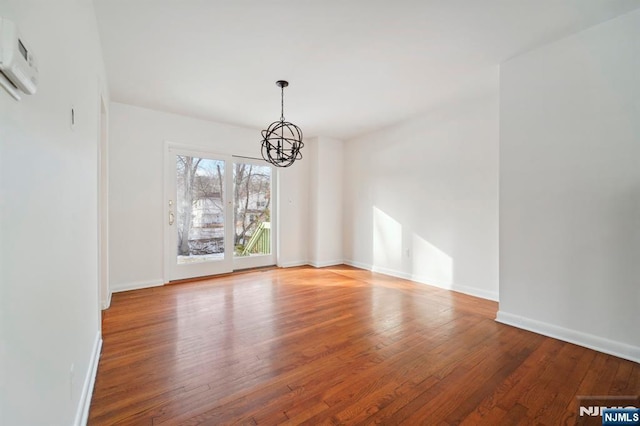 unfurnished dining area featuring baseboards, wood finished floors, and an inviting chandelier