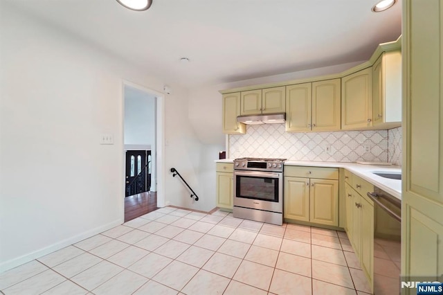 kitchen featuring light tile patterned floors, stainless steel appliances, light countertops, backsplash, and under cabinet range hood