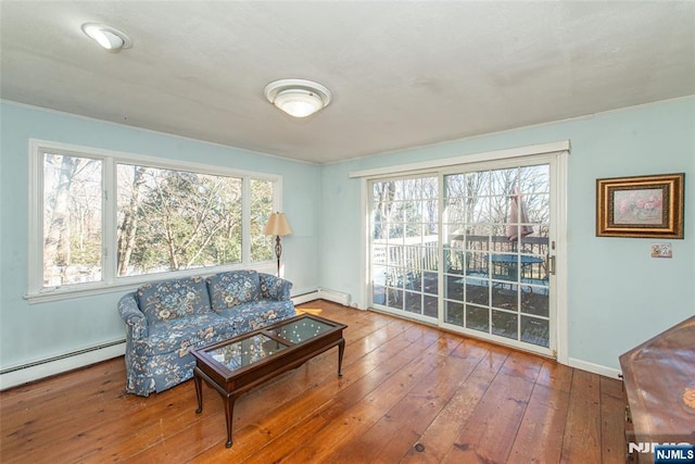 living room featuring a baseboard heating unit, a wealth of natural light, hardwood / wood-style flooring, and baseboards