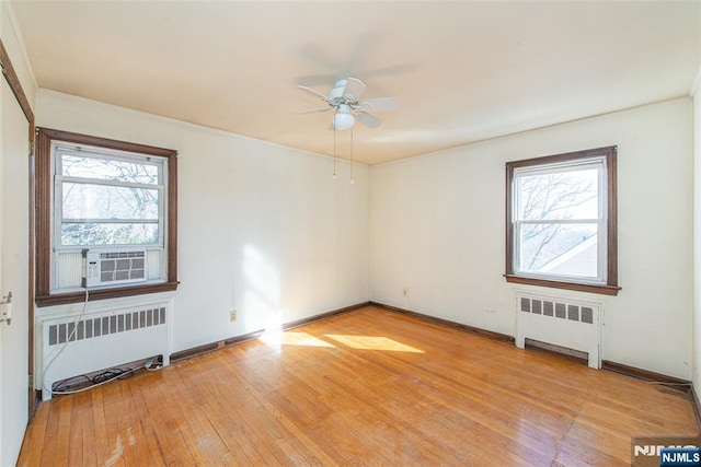 spare room with light wood-type flooring, baseboards, and radiator heating unit