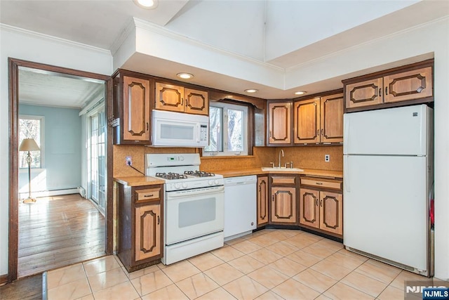 kitchen featuring white appliances, tasteful backsplash, light countertops, crown molding, and a sink