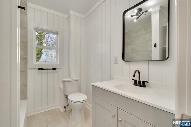 bathroom with toilet, vanity, and tile patterned floors