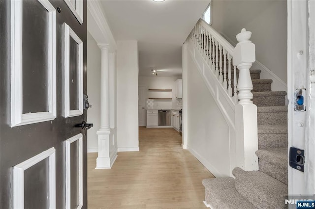 foyer entrance with stairs, ornate columns, light wood-style flooring, and baseboards