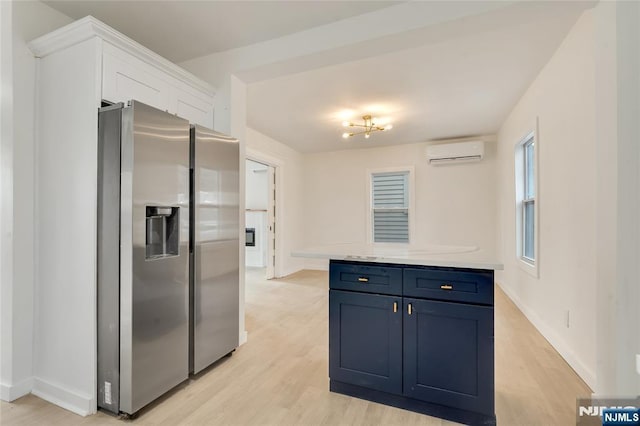 kitchen featuring blue cabinets, light wood-style floors, light countertops, an AC wall unit, and stainless steel refrigerator with ice dispenser