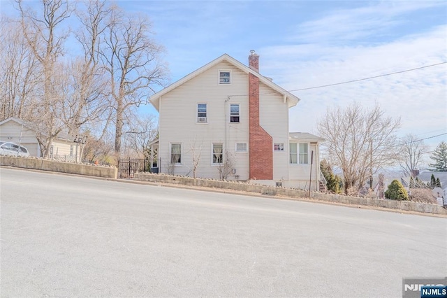 view of side of home with a chimney and fence