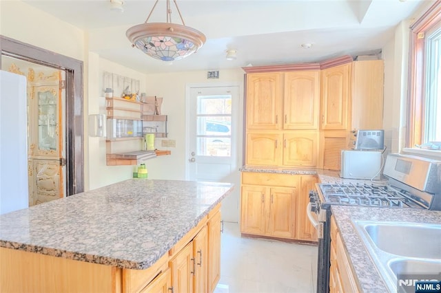 kitchen with light stone counters, white appliances, a kitchen island, and light brown cabinetry