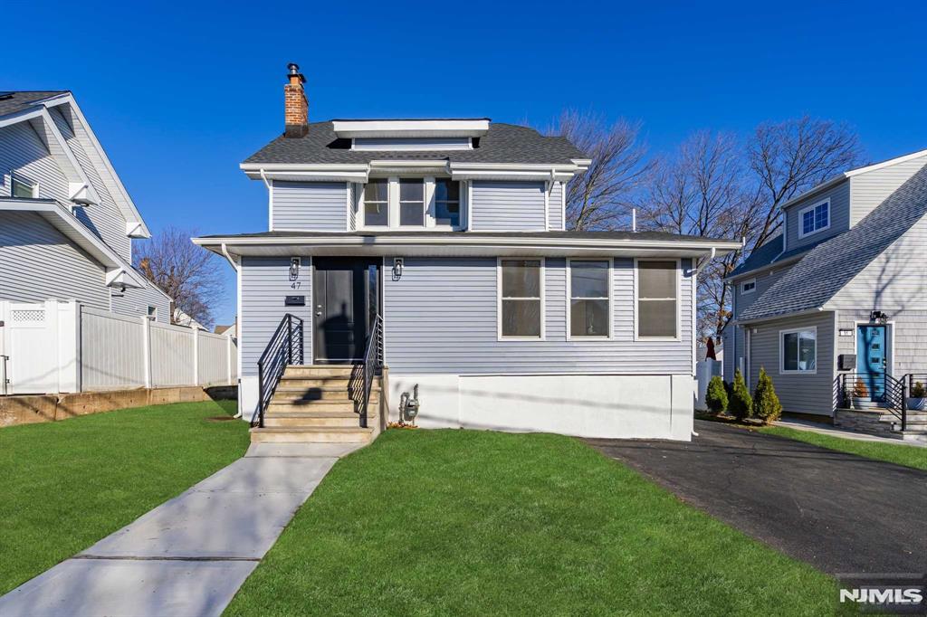 traditional style home with a shingled roof, a chimney, fence, and a front yard