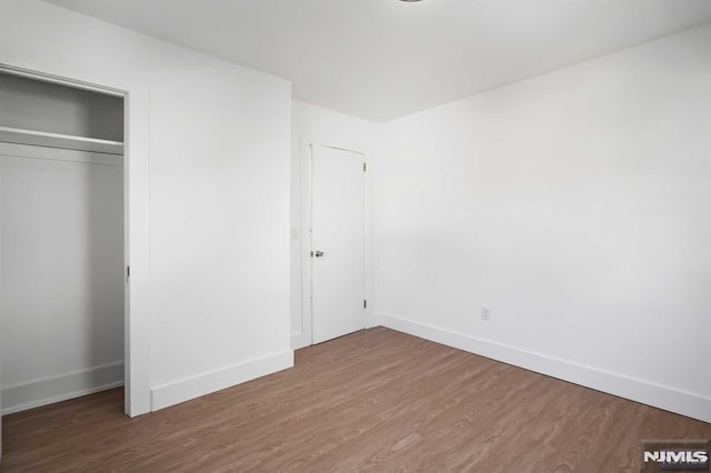 unfurnished bedroom featuring a closet, baseboards, and wood finished floors