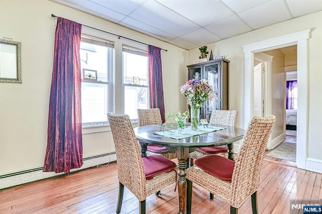 dining area with a paneled ceiling, light wood-style floors, baseboards, and baseboard heating