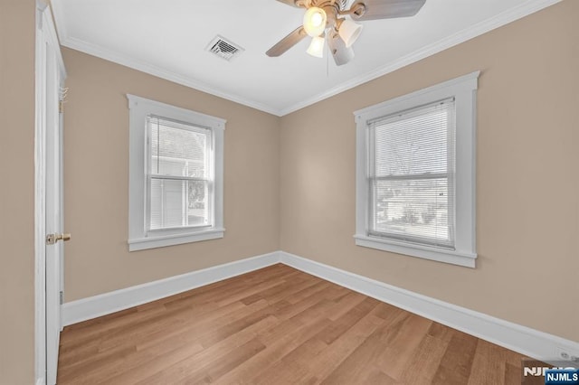 spare room with visible vents, crown molding, light wood finished floors, and baseboards