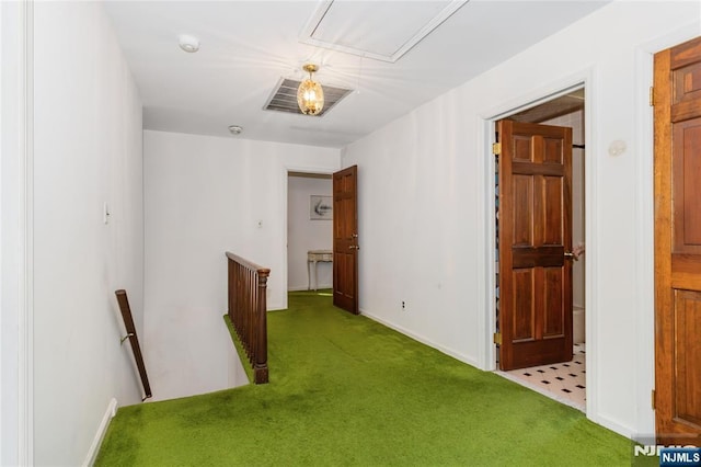 hallway featuring attic access, baseboards, carpet flooring, and an upstairs landing