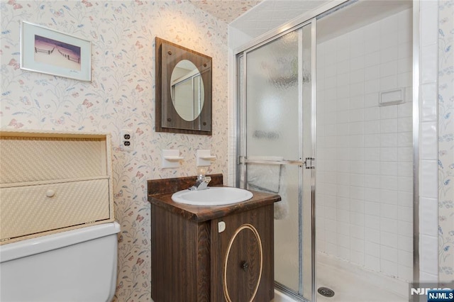 bathroom featuring a stall shower, vanity, toilet, and wallpapered walls