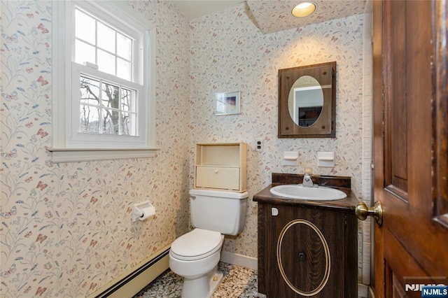 bathroom with a baseboard radiator, toilet, vanity, baseboards, and wallpapered walls