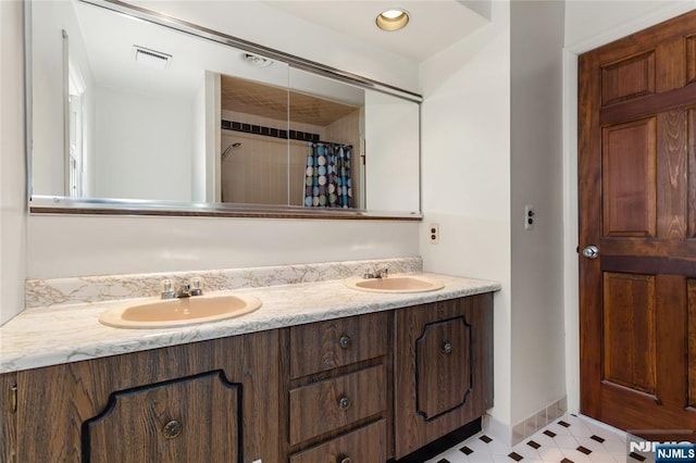 full bathroom featuring visible vents, a sink, baseboards, and double vanity