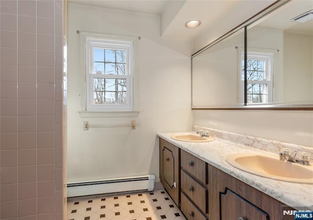 bathroom with double vanity, visible vents, baseboard heating, and a sink