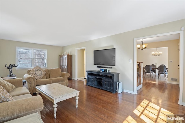 living area featuring a chandelier, visible vents, baseboards, and wood finished floors