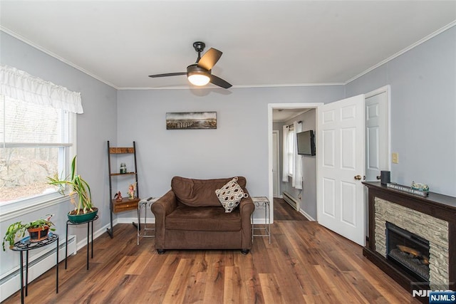 sitting room with a baseboard heating unit, wood finished floors, and ornamental molding