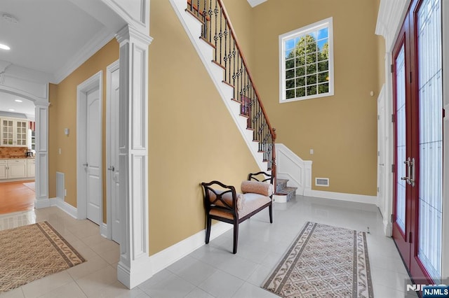 entryway featuring visible vents, baseboards, stairway, light tile patterned floors, and ornate columns