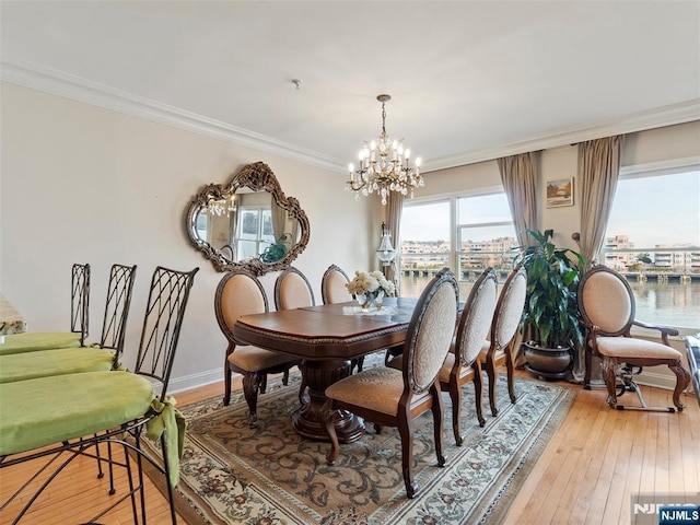 dining space with light wood-type flooring, a healthy amount of sunlight, crown molding, and a notable chandelier