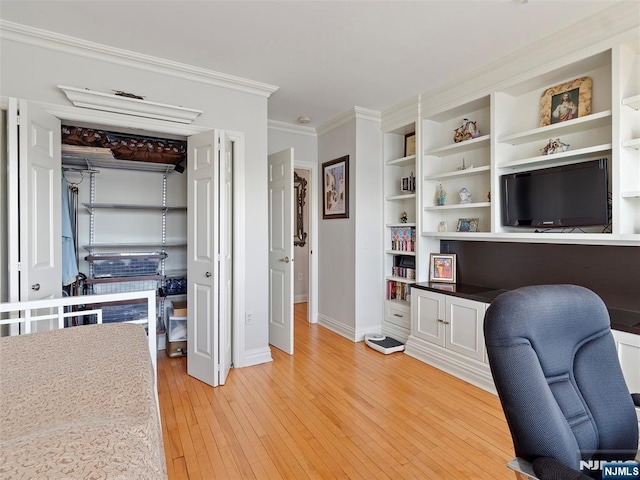 office featuring baseboards, ornamental molding, built in shelves, and light wood-style floors