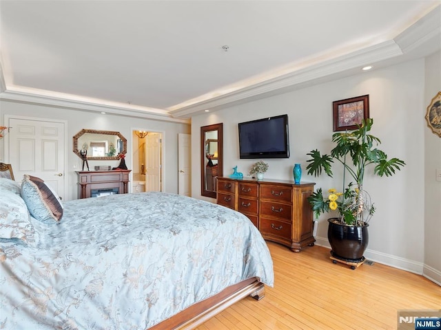 bedroom with a tray ceiling, light wood-type flooring, recessed lighting, and baseboards