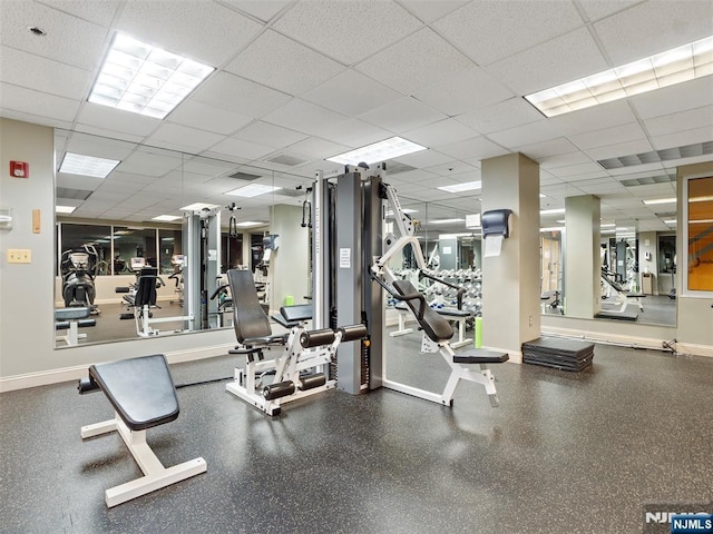 gym with baseboards and a drop ceiling