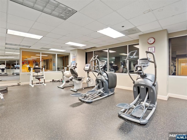 exercise room with a drop ceiling and baseboards